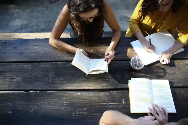 students reading books on a picnic table