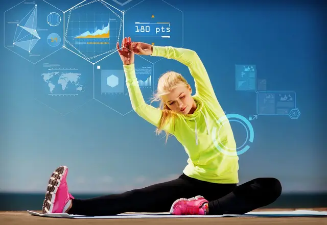 Blonde woman stretching while wearing in pink tennis shoes, bright yellow sports top, and black stretch pants.