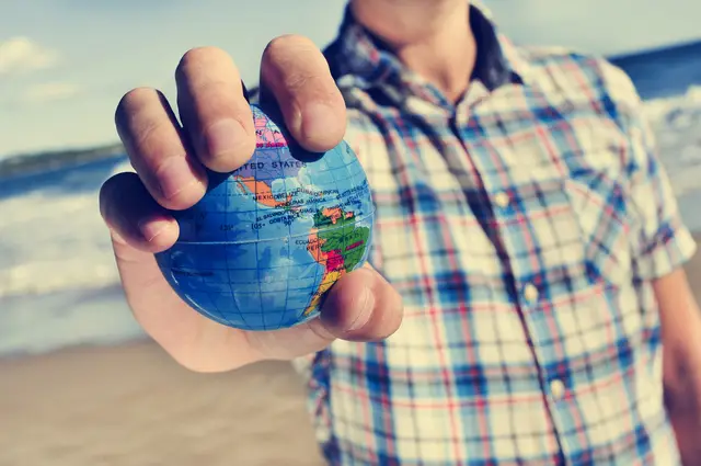 young caucasian man with a world globe in his hand