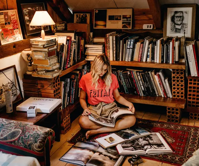 woman sitting on the floor, looking at books