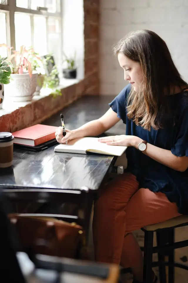 woman in a blue shirt writing in a notebook