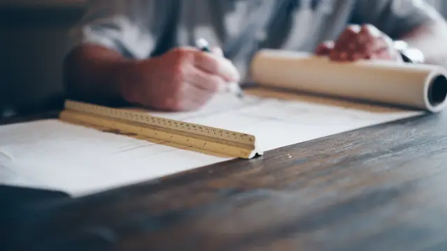 architect ruler and a person sketching with a pencil
