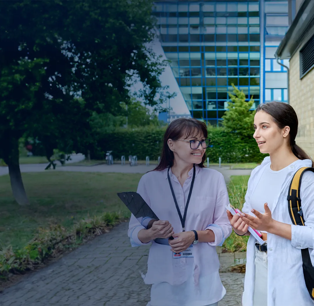 Student and counselor discussing academic success in front of school building