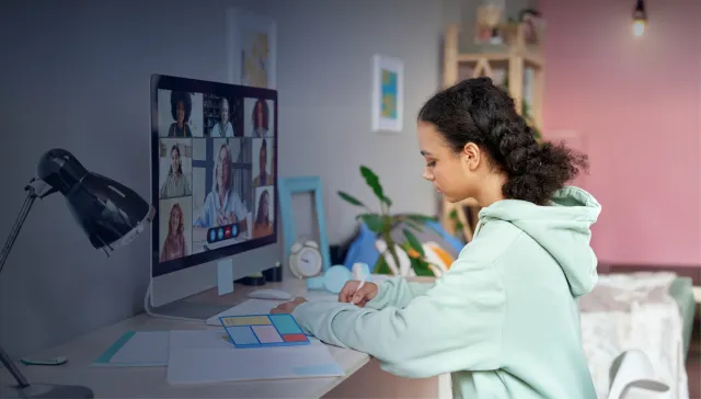 High school student taking notes while attending a webinar